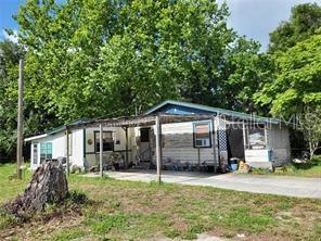 A single-story house with a covered front porch and a large tree in the yard — 5371 WARM SPRINGS AVENUE, WILDWOOD, FL