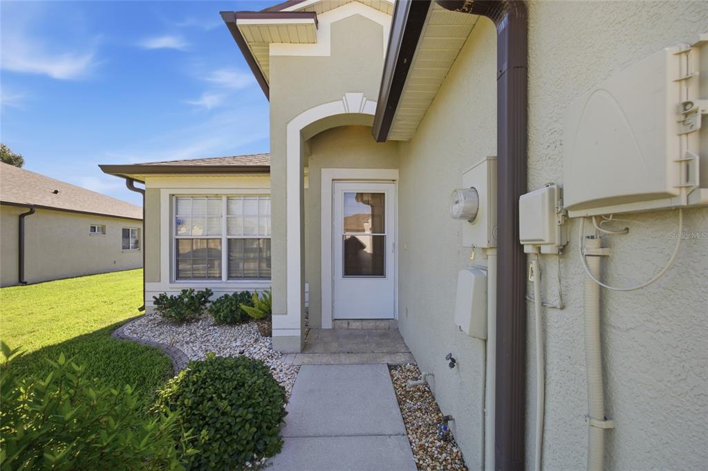 A concrete walkway leads to the front entrance of a beige stucco house — 13307 ASHBARK COURT, RIVERVIEW, FL