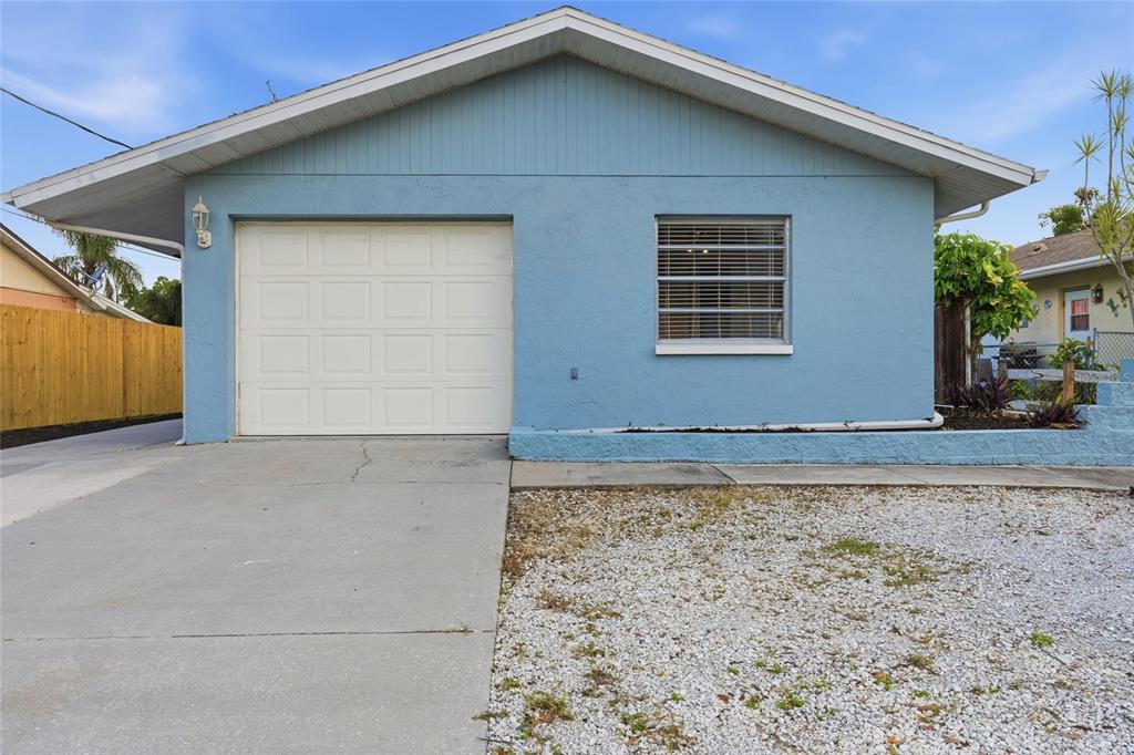 A light blue house exterior features a single-car garage, a window, and a gravel driveway — 1915 COLLEEN STREET, SARASOTA, FL