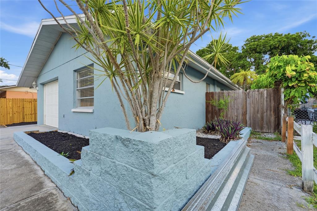 A blue house exterior features a concrete block planter and a small tree in front — 1915 COLLEEN STREET, SARASOTA, FL