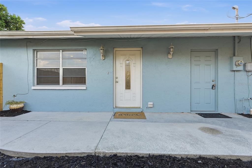 The exterior of a light blue house features a white front door and a window — 1915 COLLEEN STREET, SARASOTA, FL