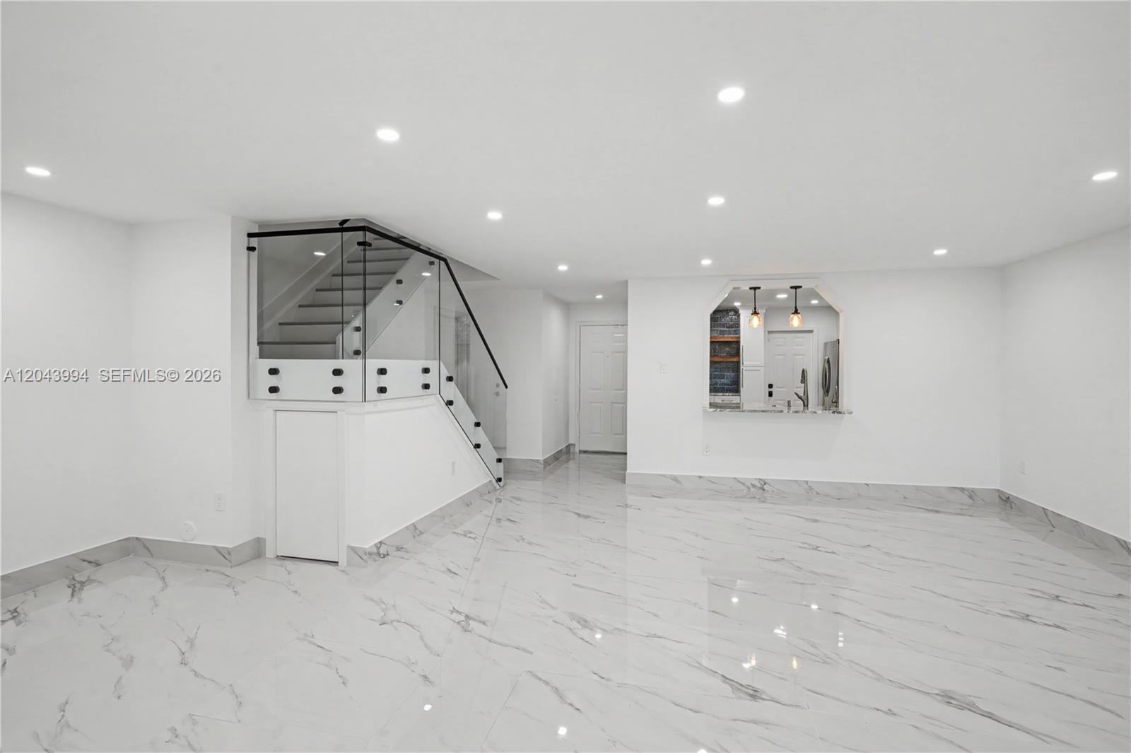 A bright, open-concept room features white marble-look tile flooring and a glass-railed staircase — 16240 SW 75th St # 0, Miami FL 33193, MIAMI, FL