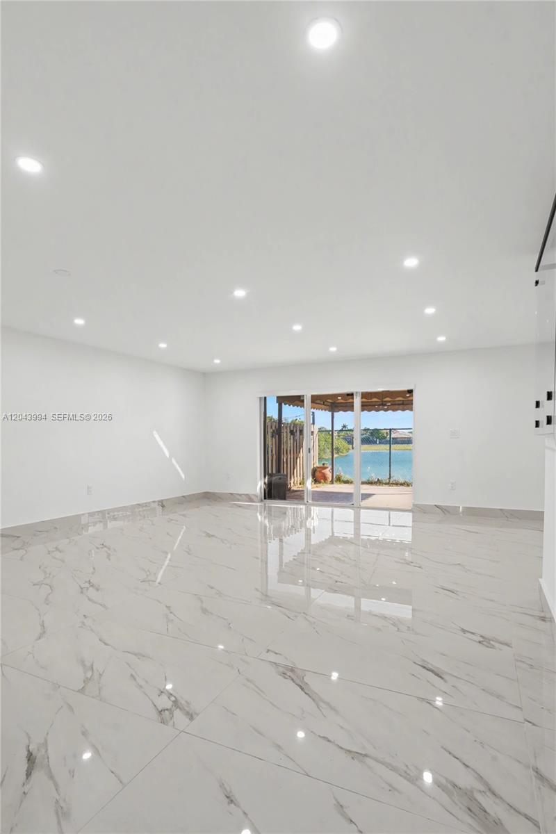 A spacious, minimalist room features white walls, recessed lighting, and polished marble-look tile flooring — 16240 SW 75th St # 0, Miami FL 33193, MIAMI, FL
