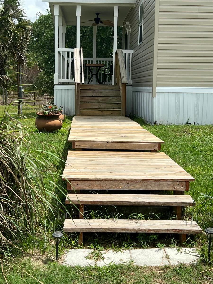 A wooden staircase and landing lead up to the screened porch of a mobile home — 15367 NW 296th Street, Okeechobee FL 34972, OKEECHOBEE, FL