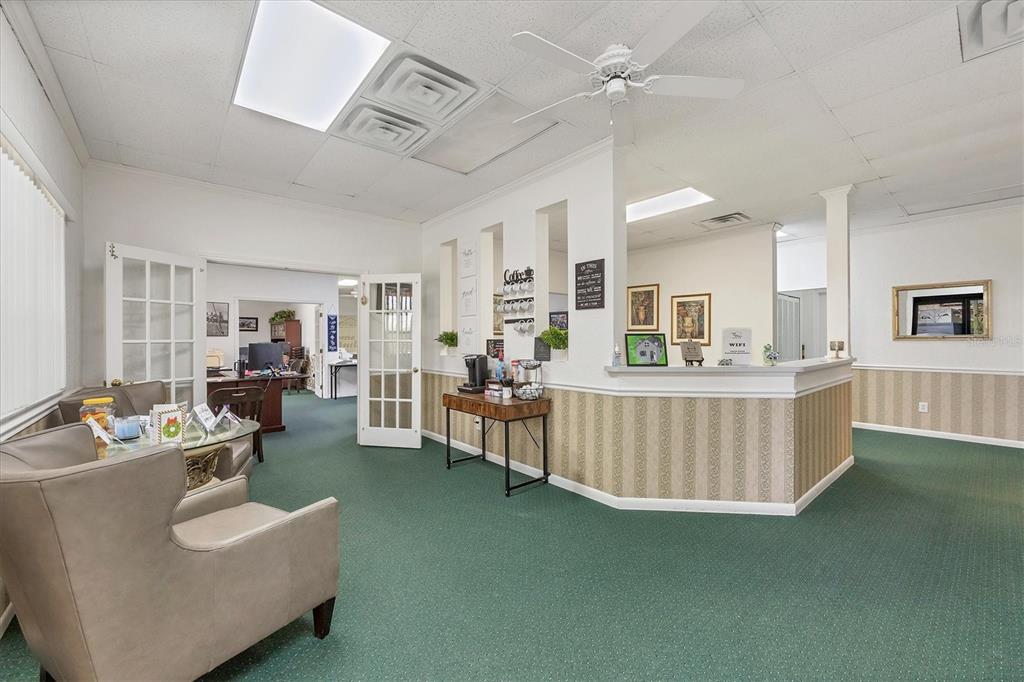 A waiting area with green carpet, beige armchairs, and a reception desk with wallpapered accents — 1578 EL JOBEAN ROAD, PORT CHARLOTTE, FL