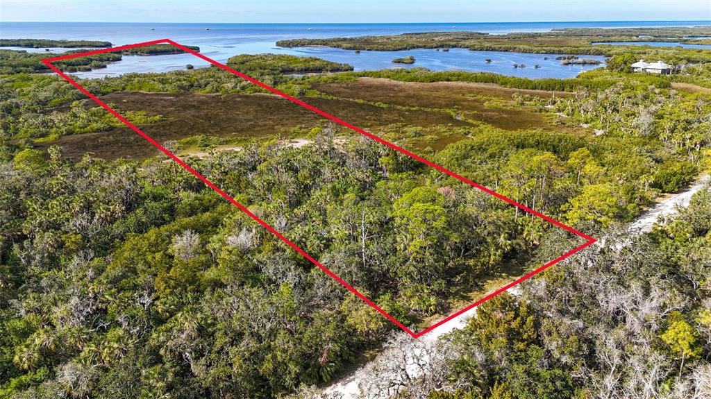 An aerial view shows a rectangular plot of land outlined in red near coastal waters — OLD POST ROAD, PORT RICHEY, FL