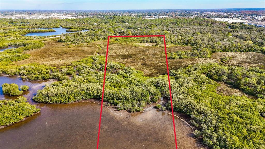 An aerial view shows a rectangular plot of land outlined in red near a waterway — OLD POST ROAD, PORT RICHEY, FL