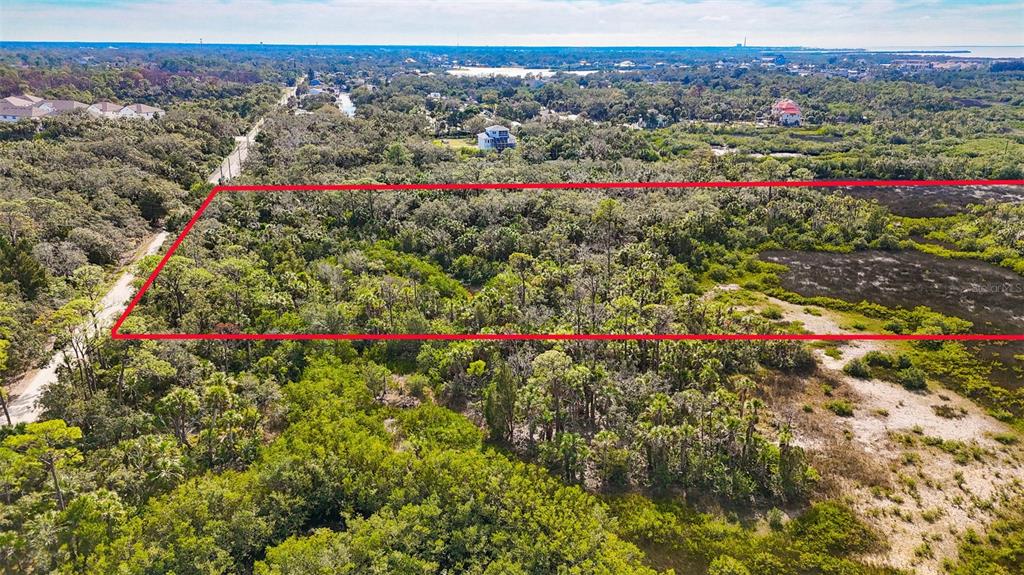 An aerial view shows a rectangular plot of land outlined in red amidst dense vegetation — OLD POST ROAD, PORT RICHEY, FL