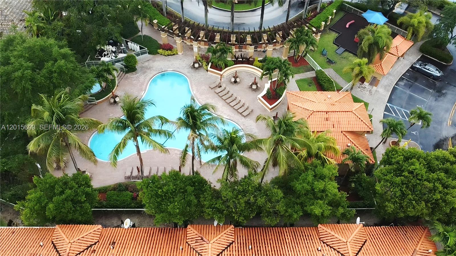 An aerial view shows a swimming pool, palm trees, and a tiled-roof building — 4950 Tradewinds Ter # 505, Dania Beach FL 33312, DANIA BEACH, FL