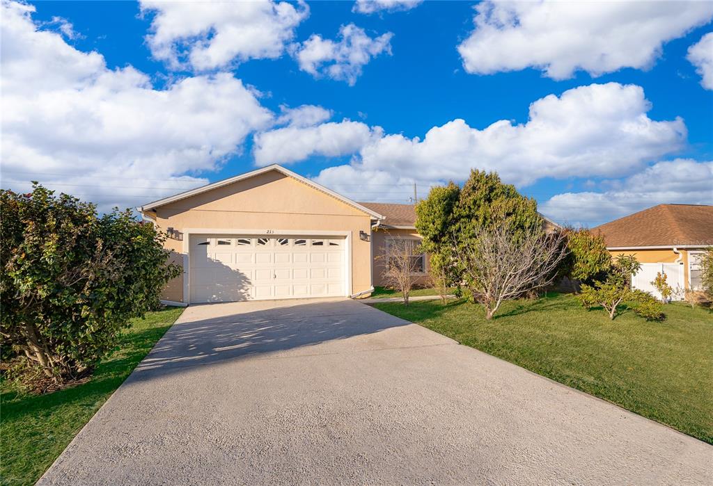 A single-story house with a beige exterior, a two-car garage, and a concrete driveway — 213 BIG BLACK DRIVE, KISSIMMEE, FL