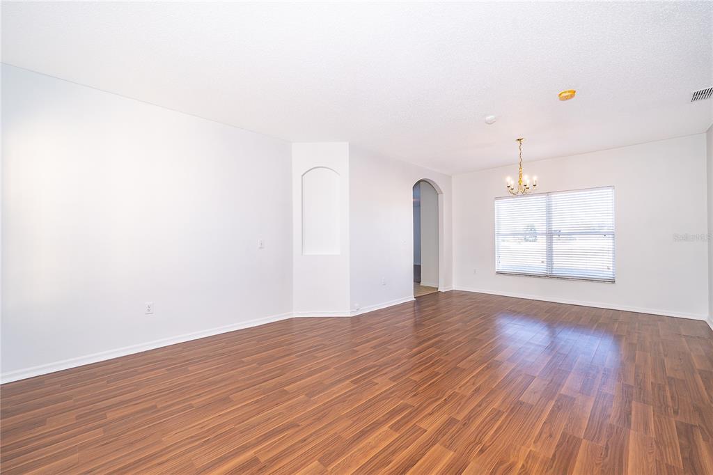 An empty dining room with wood-look flooring, white walls, and a chandelier over a window — 213 BIG BLACK DRIVE, KISSIMMEE, FL