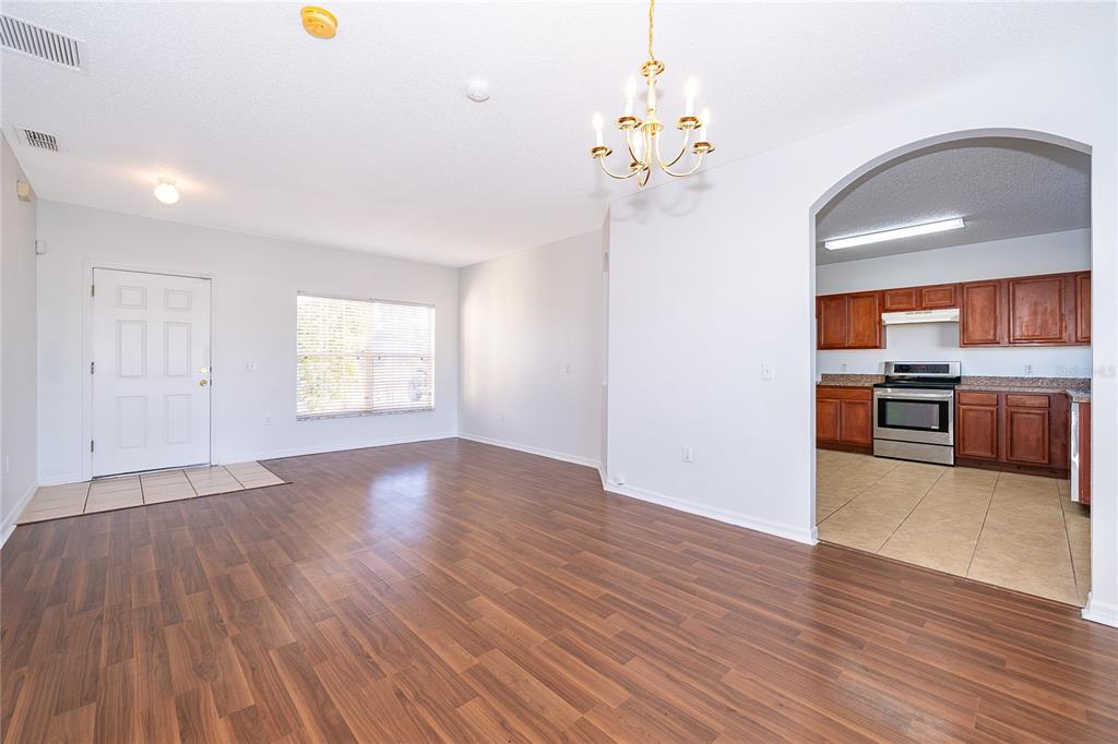 A living room with wood-look flooring leads into a kitchen through an arched doorway — 213 BIG BLACK DRIVE, KISSIMMEE, FL