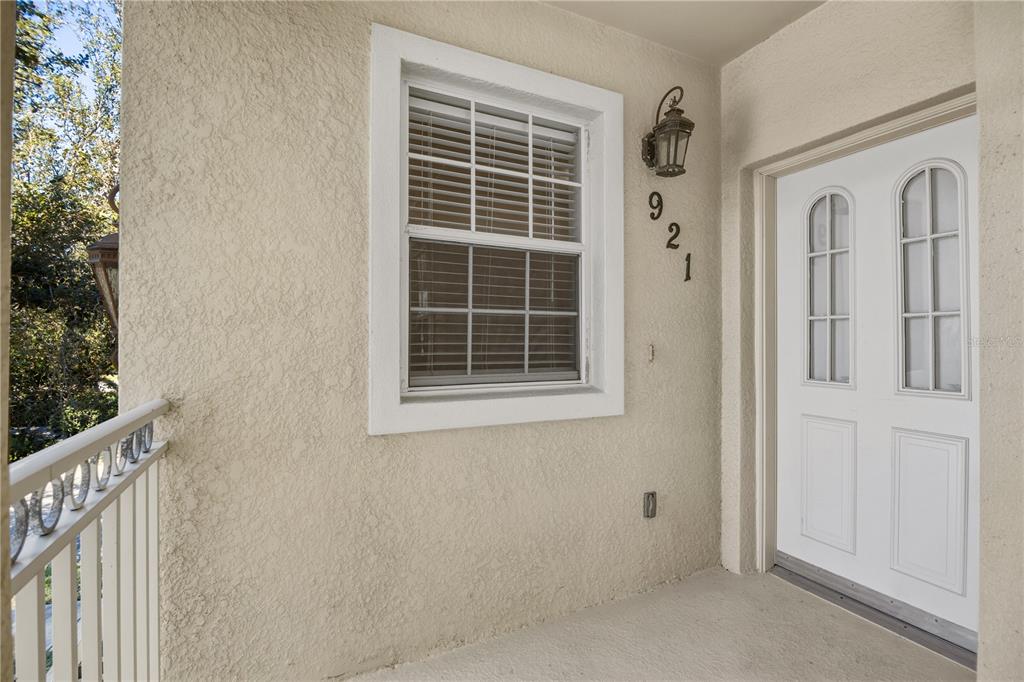 A beige stucco exterior wall features a window, a light fixture, and a white door — 900 SAN LINO CIRCLE UNIT 921, VENICE, FL