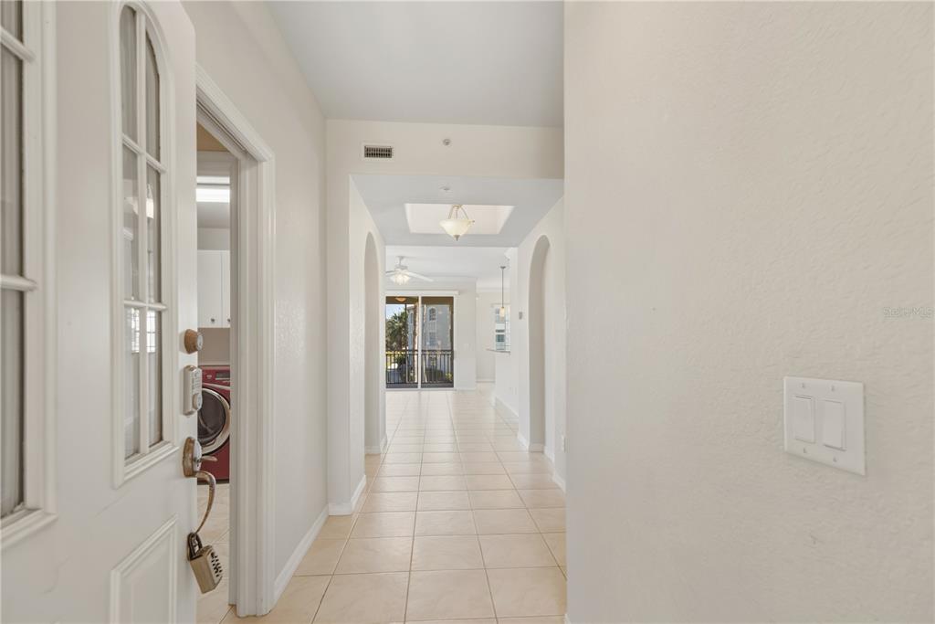 A tiled hallway leads from an entryway toward a living area with a balcony view — 900 SAN LINO CIRCLE UNIT 921, VENICE, FL