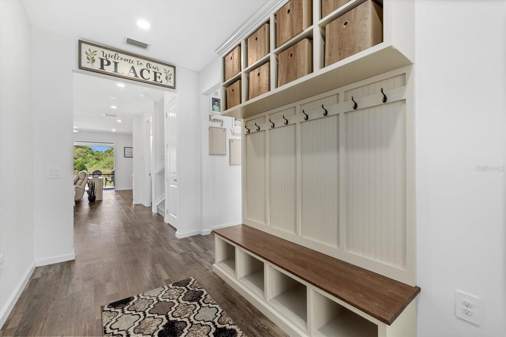 An entryway features a built-in mudroom bench with storage cubbies, coat hooks, and overhead bins — 16251 HIDDEN OAK LOOP, BRADENTON, FL