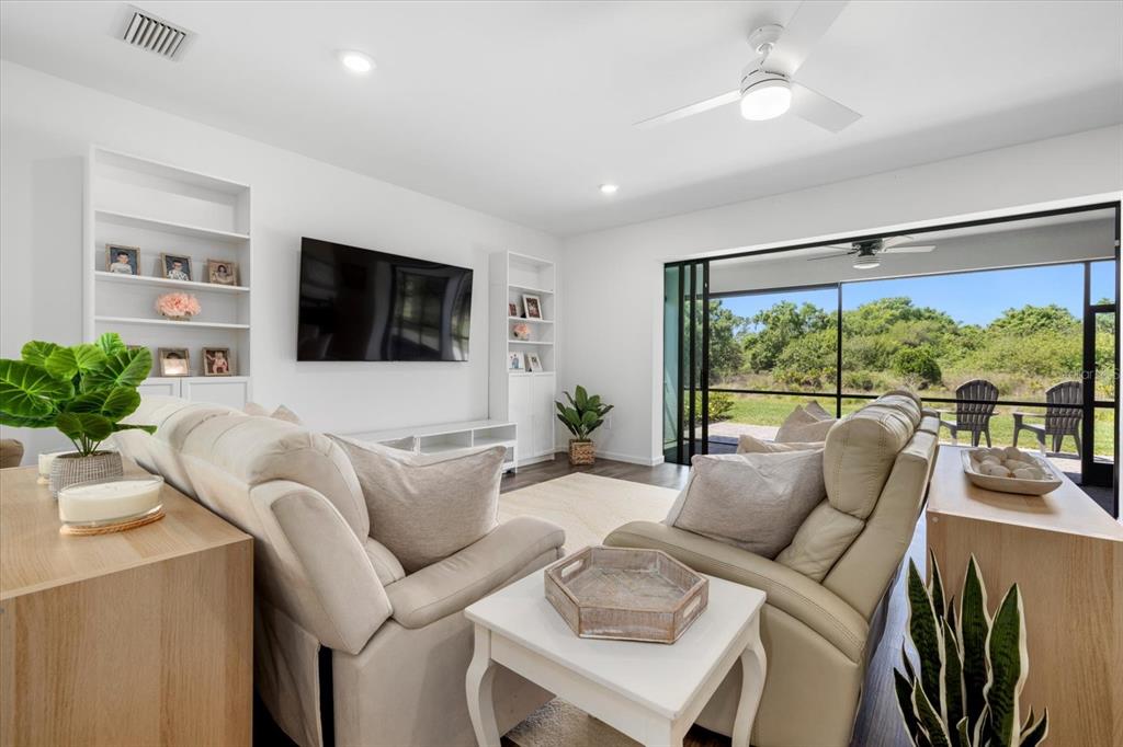 A living room with white built-in shelves, a television, and sliding doors to a patio — 16251 HIDDEN OAK LOOP, BRADENTON, FL