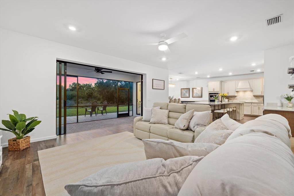 A living room with a beige sofa, area rug, and sliding doors opening to a patio — 16251 HIDDEN OAK LOOP, BRADENTON, FL