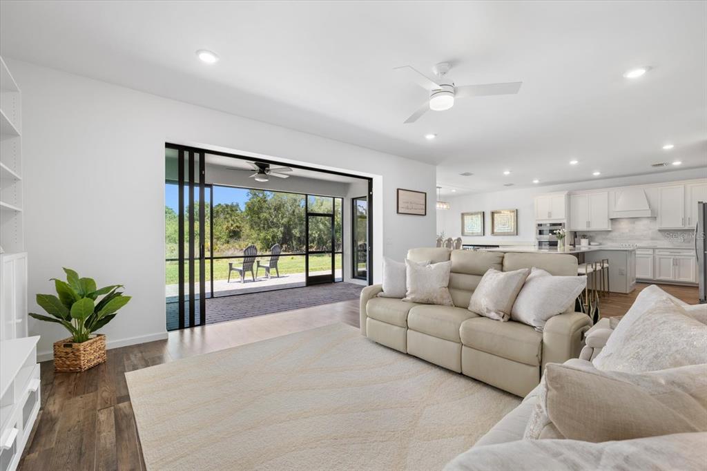 A living room with a cream sofa, area rug, and sliding doors opening to a patio — 16251 HIDDEN OAK LOOP, BRADENTON, FL