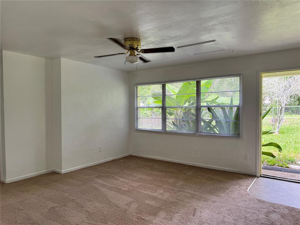 An empty room features beige carpet, white walls, a ceiling fan, and a glass door — 921 NW 55TH TERRACE, GAINESVILLE, FL