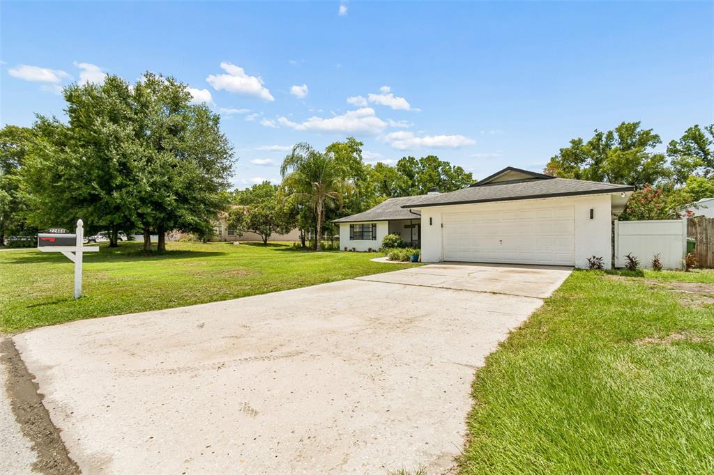 A single-story white house with a garage and a large front lawn at dusk — 22408 SHORESIDE DRIVE, LAND O LAKES, FL