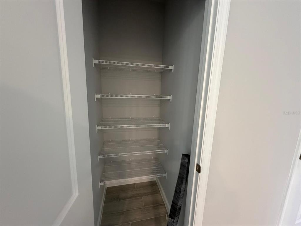 A narrow closet features five white wire shelves against gray walls and wood-look flooring — 4152 CAMPSITE LOOP, ORLANDO, FL