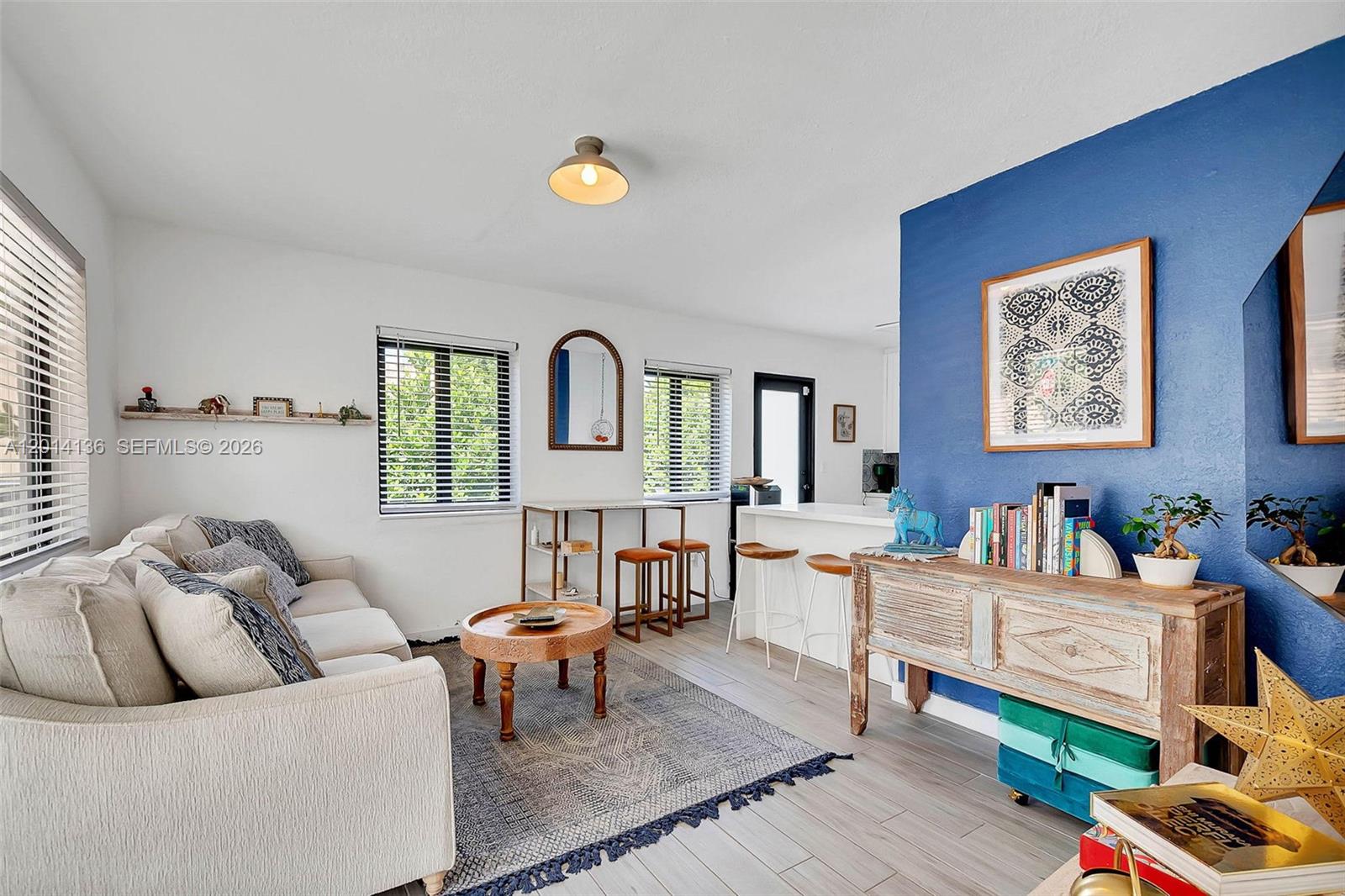 A living room features a blue accent wall, a beige sofa, and a wooden console — 595 NW 101st St, Miami FL 33150, MIAMI, FL