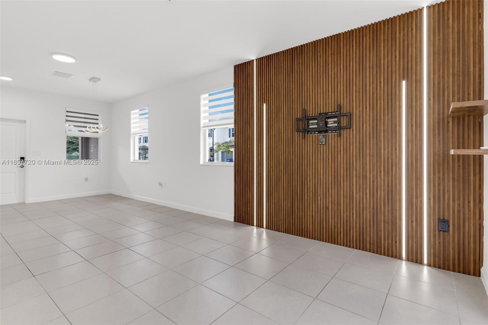 A room with light tile floors features a wood-slatted accent wall with integrated vertical lighting — 12373 NW 24th Pl, Miami FL 33167, MIAMI, FL