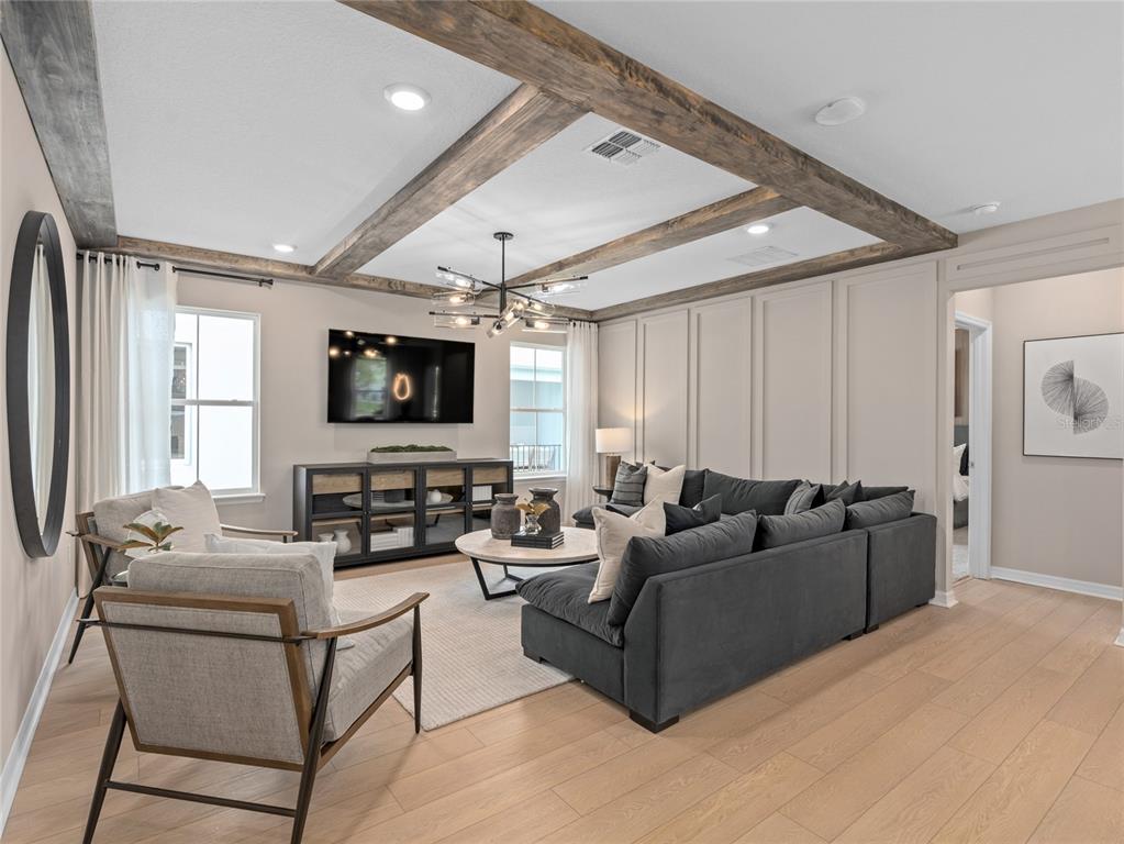 A living room features a dark sectional sofa, wood ceiling beams, and paneled walls — 10770 LEAFY LAUREL STREET, ORLANDO, FL