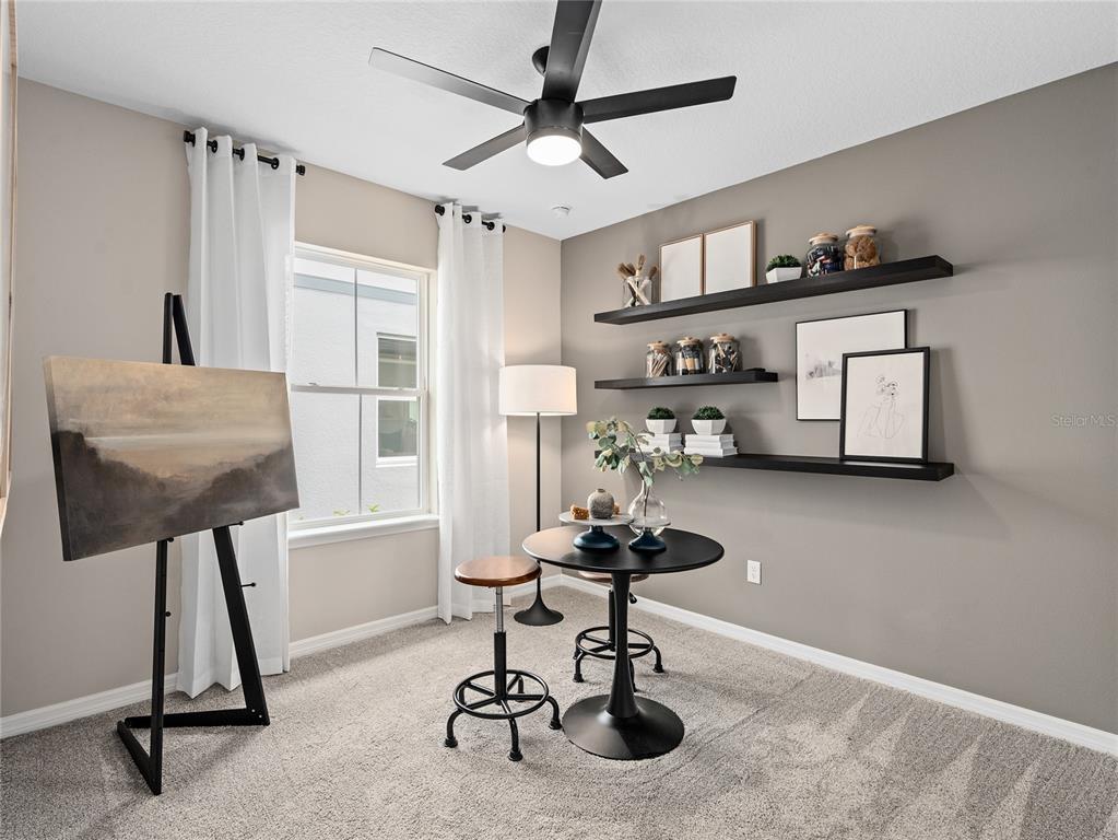 A home office features a round table, stools, an easel, and floating shelves on gray walls — 10770 LEAFY LAUREL STREET, ORLANDO, FL