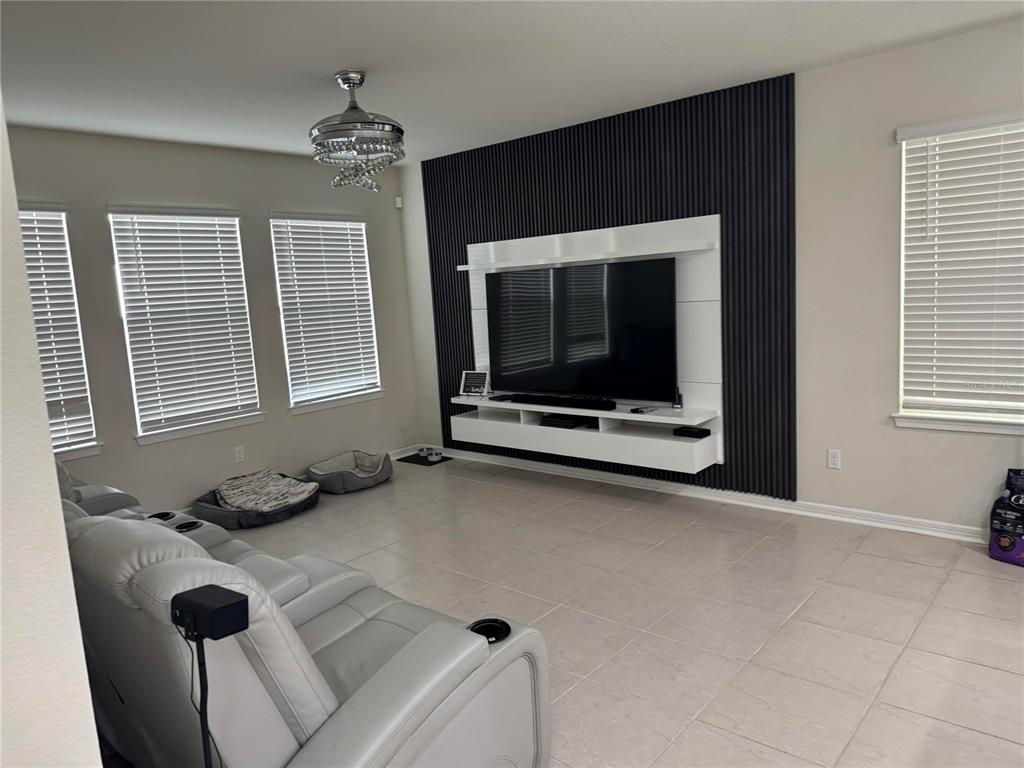 A living room features a white floating media console against a black slatted accent wall — 1877 SUMMER SERENITY DRIVE, KISSIMMEE, FL