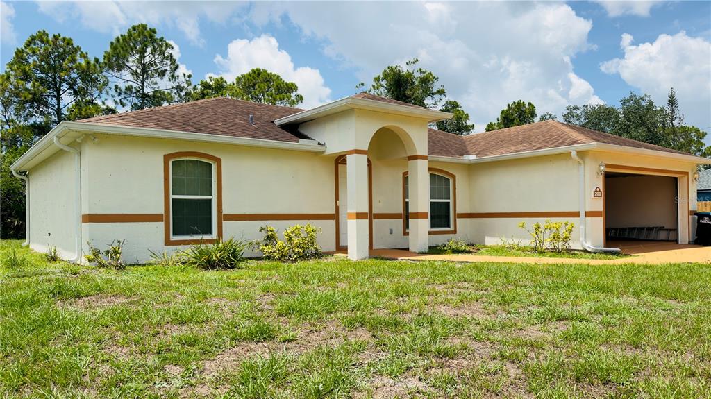 A single-story house with a beige stucco exterior, brown roof, and an attached two-car garage — 200 BREAKWATER STREET SE, PALM BAY, FL