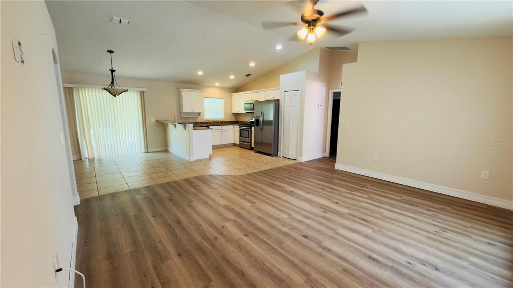 An open-concept living area features wood-look flooring, a kitchen with white cabinets, and tile flooring — 200 BREAKWATER STREET SE, PALM BAY, FL