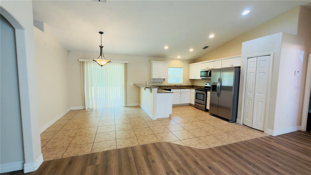 A kitchen and dining area with tile flooring, white cabinets, and stainless steel appliances — 200 BREAKWATER STREET SE, PALM BAY, FL