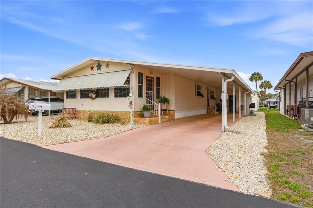A single-story manufactured home with a carport, beige siding, and a gravel front yard — 4511 REDWOOD STREET, WINTER HAVEN, FL