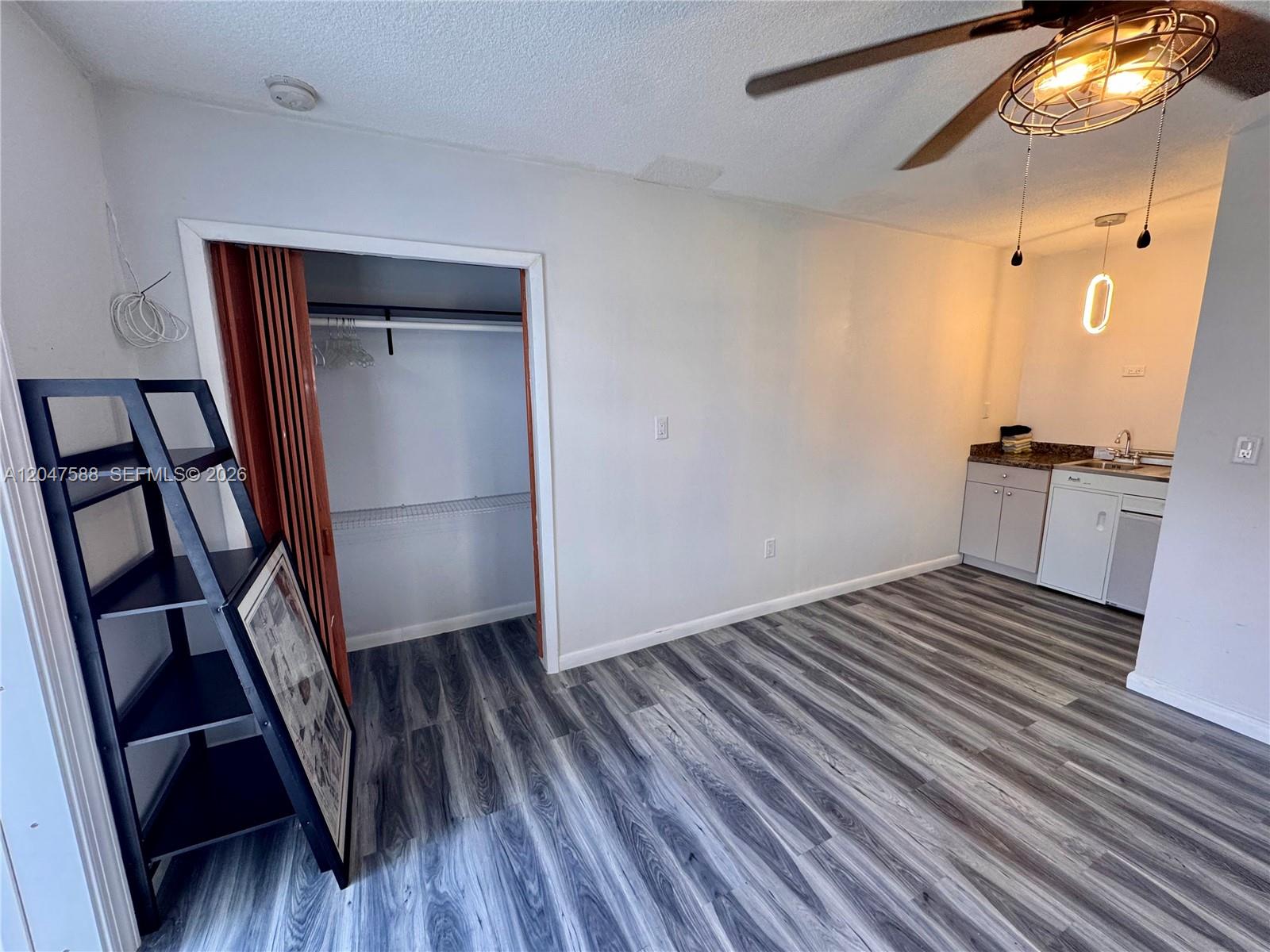 A studio apartment features wood-look flooring, a small kitchenette, and a closet with accordion doors — 1158 NW 34th Ave # 2, Miami FL 33125, MIAMI, FL