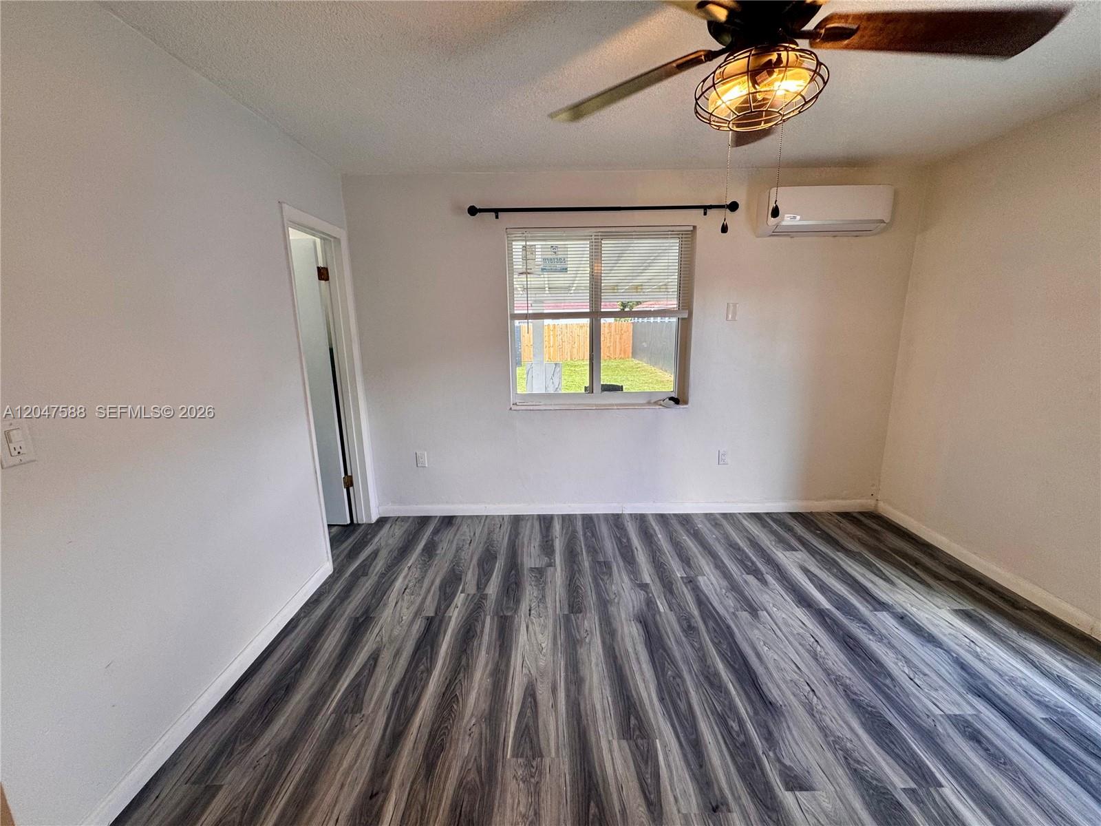 A bedroom features gray wood-look flooring, a ceiling fan, and a wall-mounted air conditioner — 1158 NW 34th Ave # 2, Miami FL 33125, MIAMI, FL