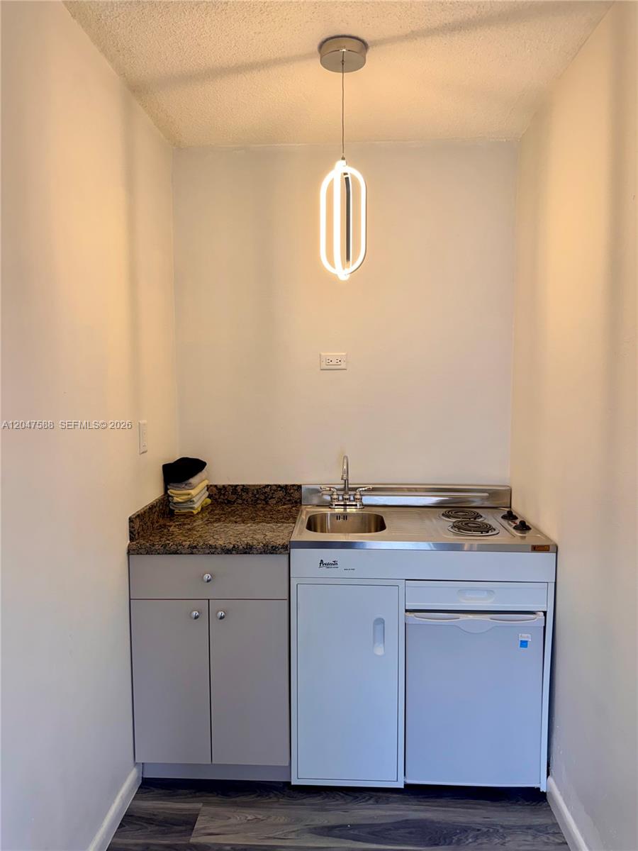 A small kitchenette features a compact unit with a sink, stovetop, and refrigerator — 1158 NW 34th Ave # 2, Miami FL 33125, MIAMI, FL