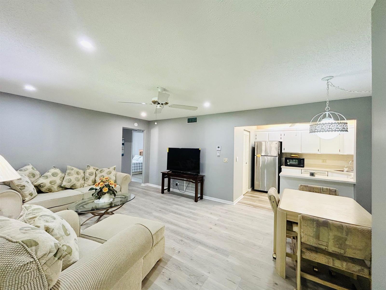 An open-concept living and dining area features light wood-look flooring and a neutral color palette — 408 Pine Glen Lane # 2, FL 33463, FL