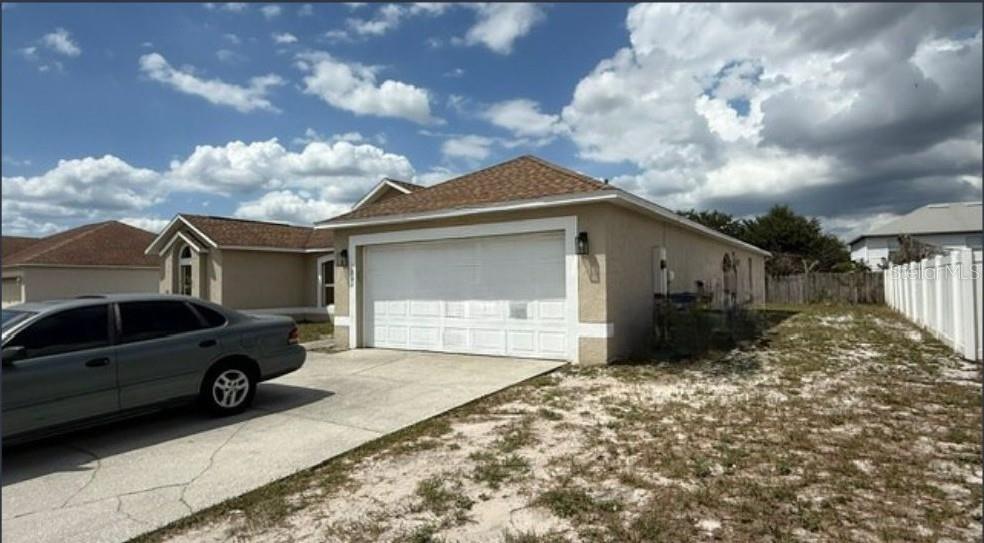 A tan house with a two-car garage and a concrete driveway under a cloudy sky — 1861 ASHTON PARK PLACE, ST CLOUD, FL