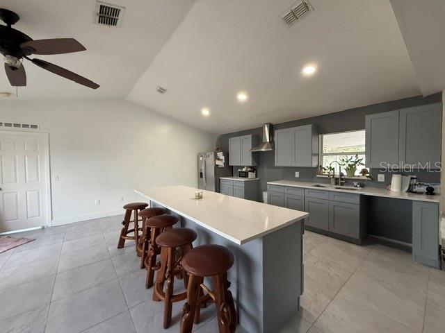 A kitchen features a large white island with wooden stools, gray cabinets, and tile flooring — 1861 ASHTON PARK PLACE, ST CLOUD, FL