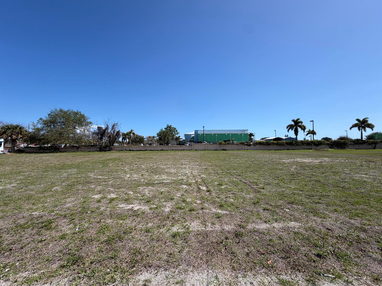 A large, flat, grassy vacant lot under a clear blue sky — 705 SE Tarpon Avenue, Stuart FL 34994, STUART, FL