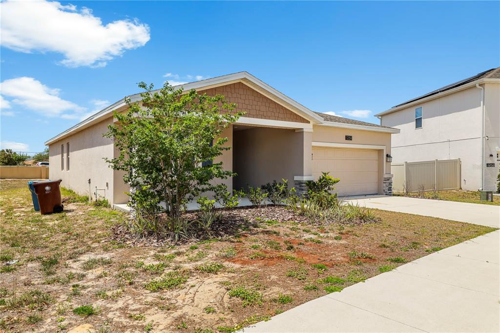 A single-story house with a tan stucco exterior, a two-car garage, and a front yard — 1259 LASSEN STREET, HAINES CITY, FL