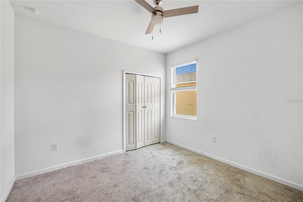 An empty bedroom features white walls, gray carpet, a ceiling fan, and a bi-fold closet — 1259 LASSEN STREET, HAINES CITY, FL