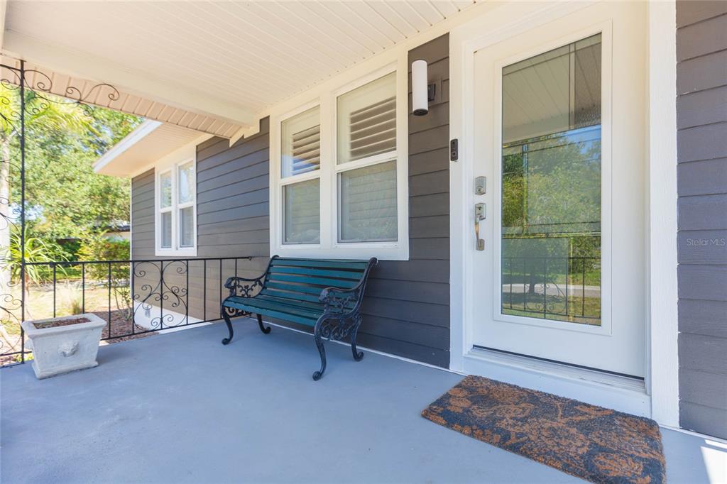 A covered porch features gray siding, a white front door, and a green metal bench — 602 W HILDA STREET, TAMPA, FL