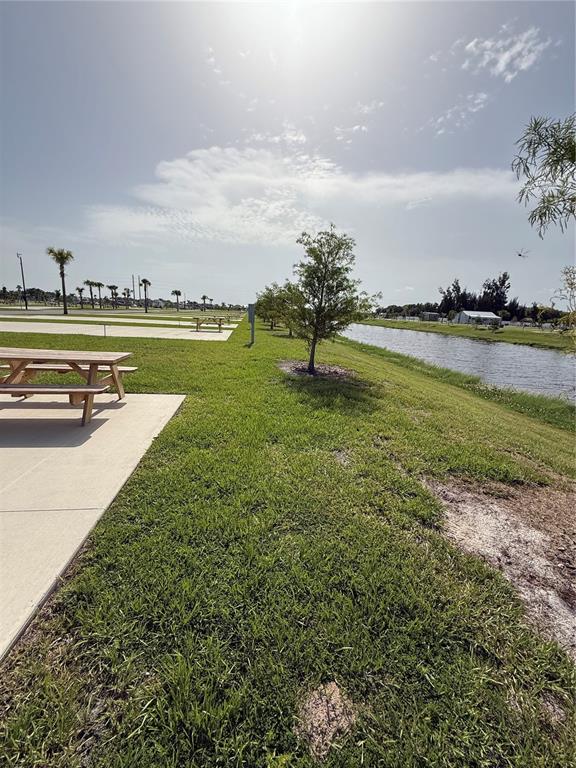 A picnic table sits on a concrete pad next to a grassy lawn and canal — 201 DELTA DRIVE, PUNTA GORDA, FL