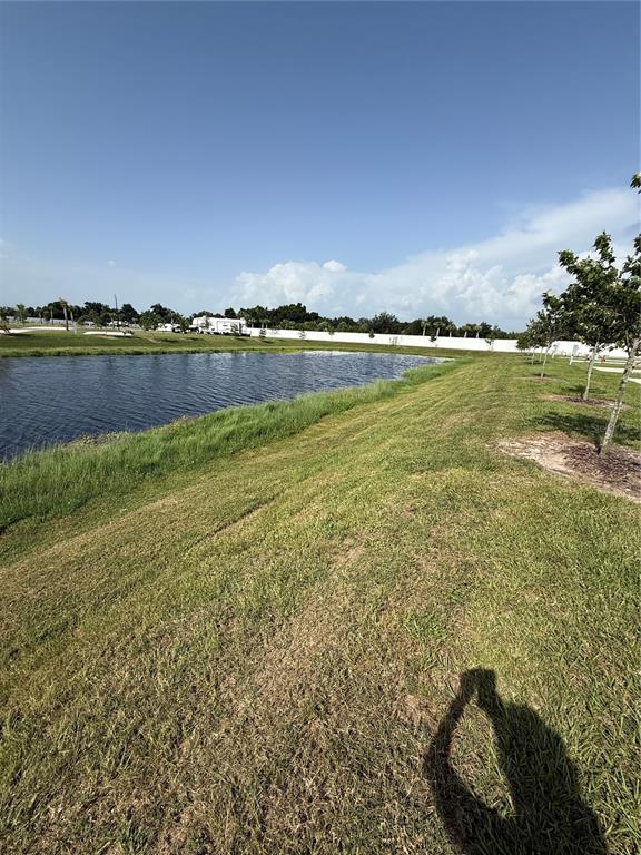 A grassy slope leads down to a pond under a clear blue sky — 201 DELTA DRIVE, PUNTA GORDA, FL