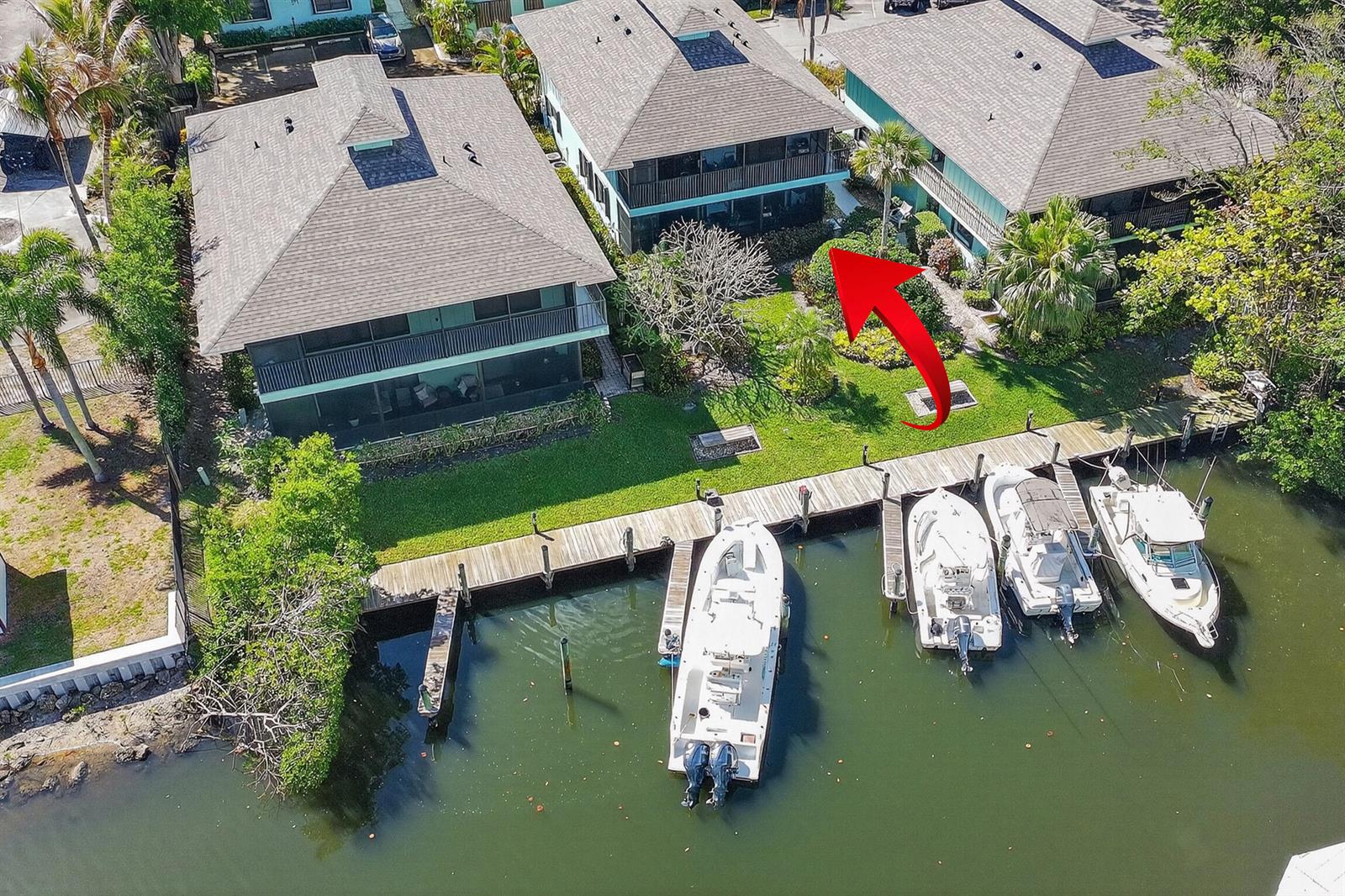 An aerial view shows three multi-story buildings with balconies situated along a canal with docks — 4083 SE Centerboard Lane # a, Stuart FL 34997, STUART, FL