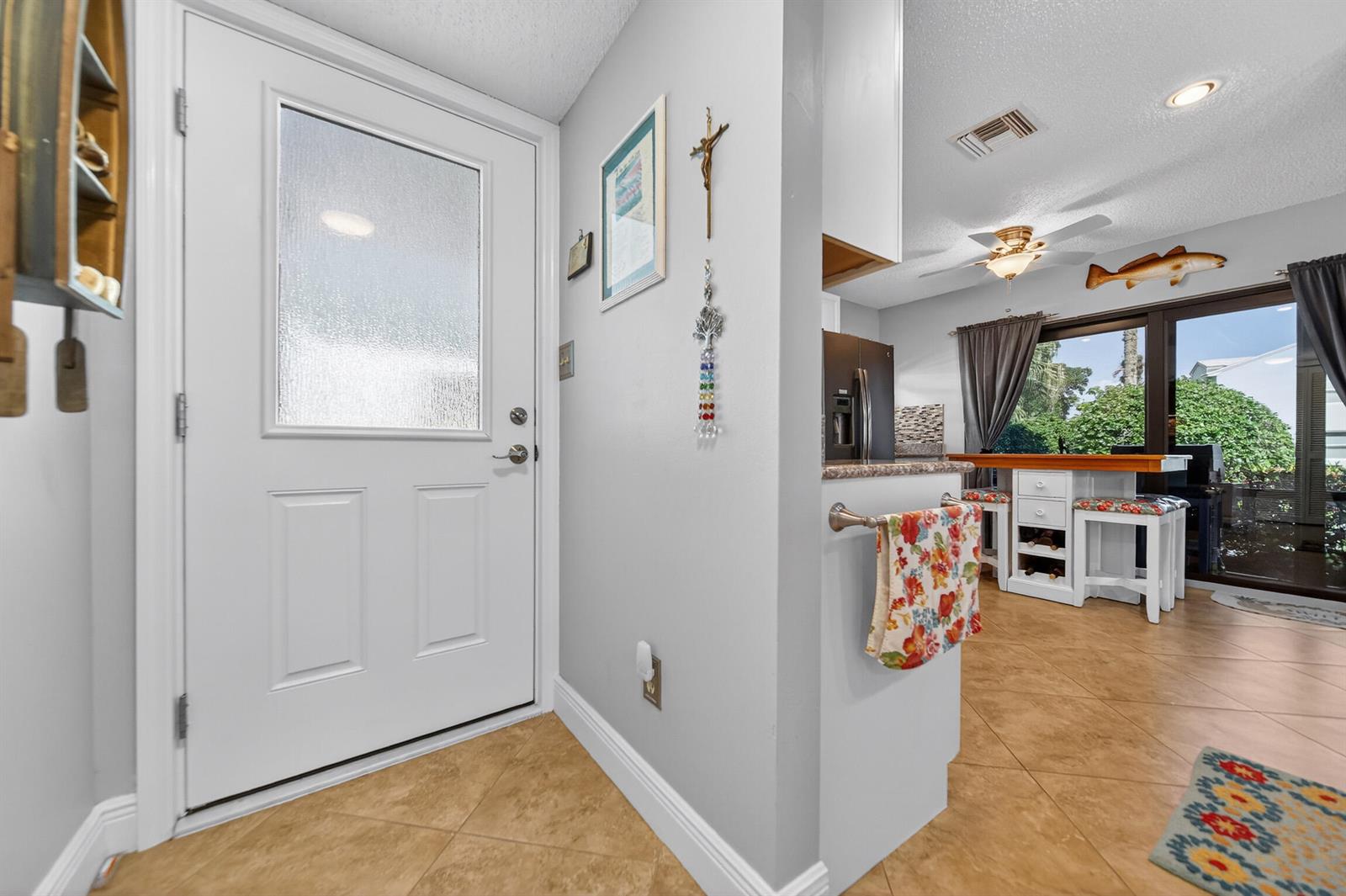 An entryway with a white door leads into a kitchen area with tile flooring — 4083 SE Centerboard Lane # a, Stuart FL 34997, STUART, FL
