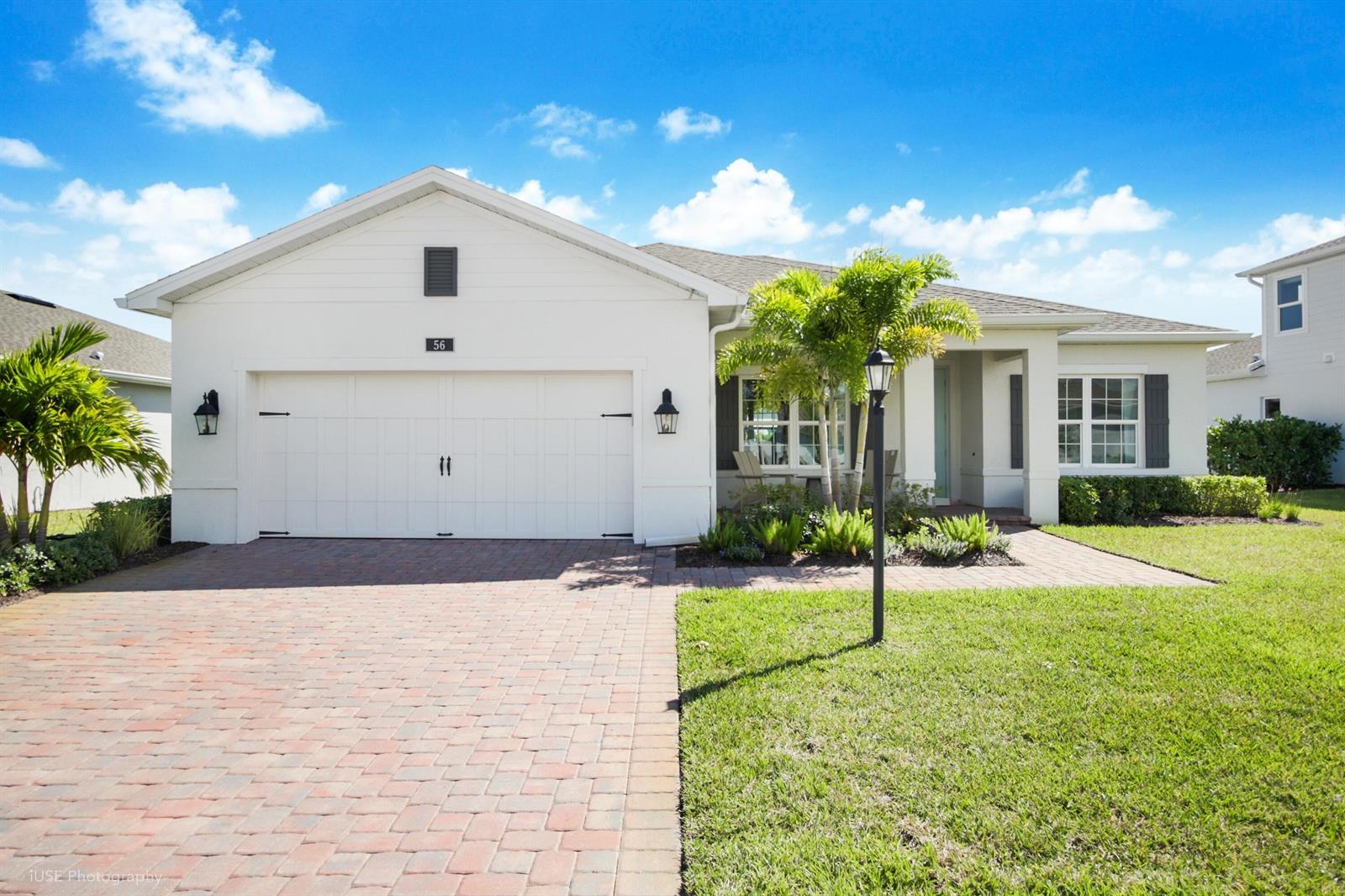 A white single-story house features a brick driveway, a two-car garage, and palm trees — 56 Judah Lane, Sebastian FL 32958, SEBASTIAN, FL