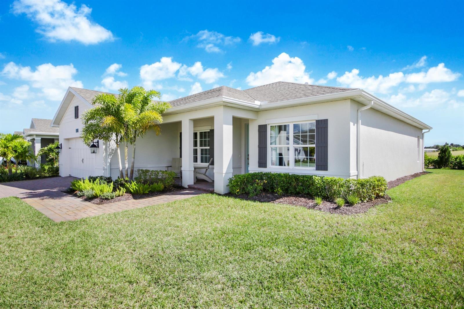 A single-story house with a white stucco exterior, dark shutters, and a paved walkway — 56 Judah Lane, Sebastian FL 32958, SEBASTIAN, FL